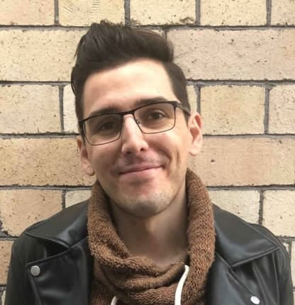 Portrait photo of Istvan standing in front of a brick wall.